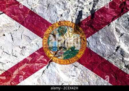 Drapeau national de l'état de Floride USA représentant une fille avec des fleurs sur le bord de mer et un voilier sur Jour de l'indépendance peint sur un rocher de montagne Banque D'Images