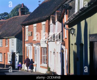 Mère et fille marchant le long de l'ancienne boulangerie dans le village de Castle Hedingham, Essex, Angleterre, Royaume-Uni Banque D'Images