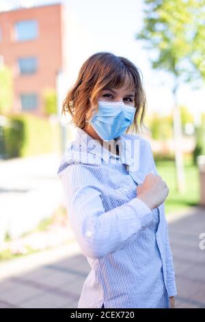 Femme en masque saluant avec coude à l'extérieur dans le parc pendant pandémie Banque D'Images