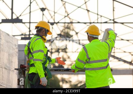 Ingénieurs et travailleurs asiatiques consultés ensemble pour la planification et le développement de la construction le contexte est la structure du toit, concept de construction Banque D'Images