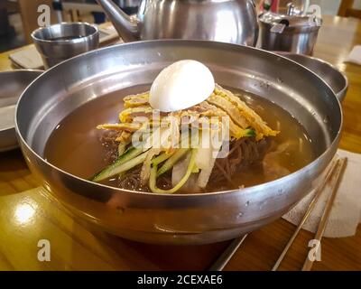 Jinju Naengmyeon, plat de nouilles faites à la main à base de sarrasin et bouillon froid à base de bœuf. Surmontée de Yukjeon, crêpe de bœuf de style coréen. Banque D'Images