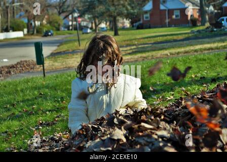 jeune fille jouant dans un tas de feuilles Banque D'Images