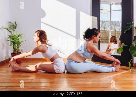 Vue latérale des femmes tranquilles dans les vêtements de sport De retour à Pascimottanasana avec les yeux fermés et la pratique de la pleine conscience pendant faire du yoga Banque D'Images