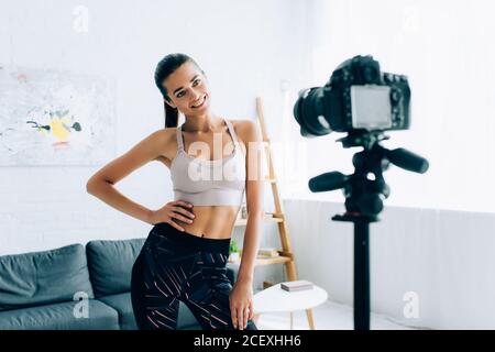 Mise au point sélective de sportswoman avec la main sur la hanche appareil photo numérique à la maison Banque D'Images