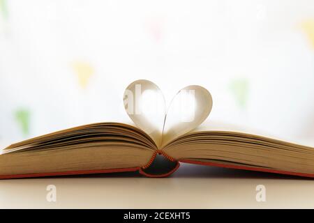 Gros plan du livre ouvert avec des pages en forme de coeur placé sur une table dans une pièce lumineuse Banque D'Images