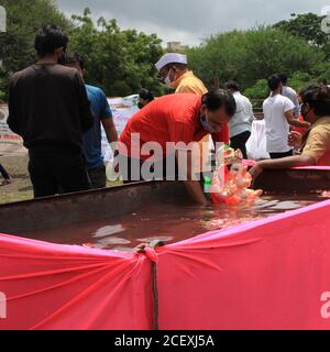 Homme immergeant l'idole de Lord Ganesha dans un réservoir communautaire le dernier jour du festival annuel de Ganesha. Lieu: Nashik, Maharashtra, Inde. Date : sept Banque D'Images