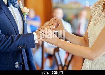 Vue latérale des anneaux de mariage de la petite mariée et du marié pendant la cérémonie dans l'église Banque D'Images