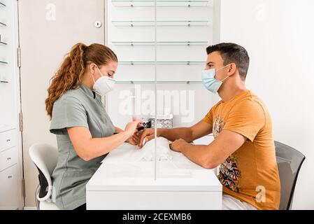 Vue latérale d'un jeune homme dans un masque de protection professionnel une manucure de femme spécialiste du centre de beauté moderne Banque D'Images