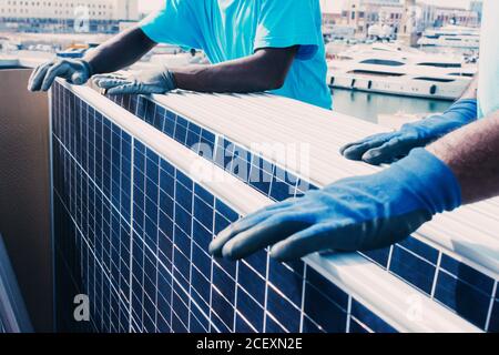 Croissez des hommes afro-américains méconnus en portant des gants de protection panneaux solaires contemporains dans la zone industrielle de l'usine pendant la journée Banque D'Images