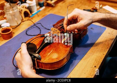 Rognez l'artisan anonyme qui définit le poste sonore tout en construisant un instrument à cordes en atelier Banque D'Images