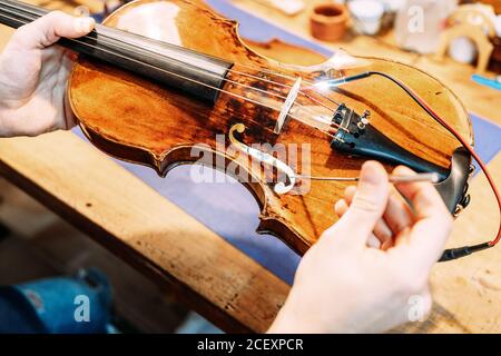 Rognez l'artisan anonyme qui définit le poste sonore tout en construisant un instrument à cordes en atelier Banque D'Images