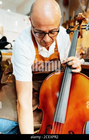 Instrument professionnel de vérification de luthier d'artisan senior pendant le travail atelier Banque D'Images