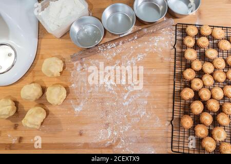 Vue de dessus de comptoir en bois avec des formes métalliques et frais biscuits sur la grille de refroidissement et morceaux de pâte Banque D'Images