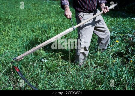 L'homme qui coupe l'herbe avec un scythe. Arrière-plan, gros plan. Banque D'Images