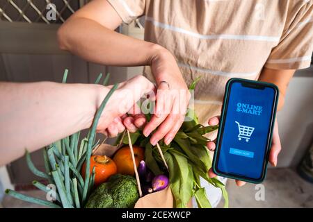 femme méconnue avec smartphone avec application mobile pour les achats en ligne prendre des provisions fraîches de liveur Banque D'Images
