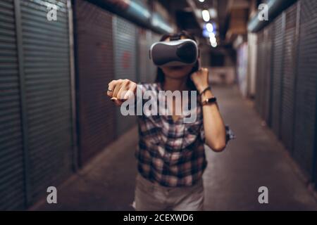 Calme femme se tenant sur une rue étroite de chichabby et en pleine expérience virtuelle La réalité en portant des lunettes VR sans fil Banque D'Images