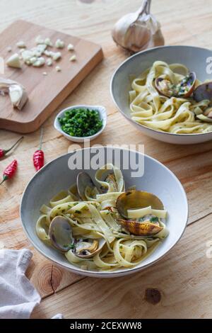 Grand angle de bol de spaghetti fraîchement cuits avec des palourdes placé sur une table en bois dans le café Banque D'Images