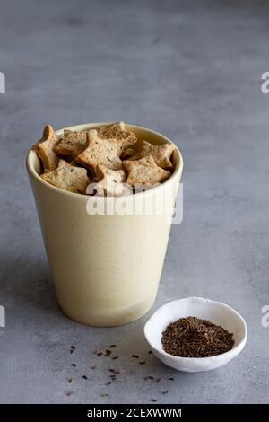 Appétissant biscuits salés faits maison en forme d'étoile avec graines de cumin servis dans une tasse en céramique sur une table en marbre Banque D'Images