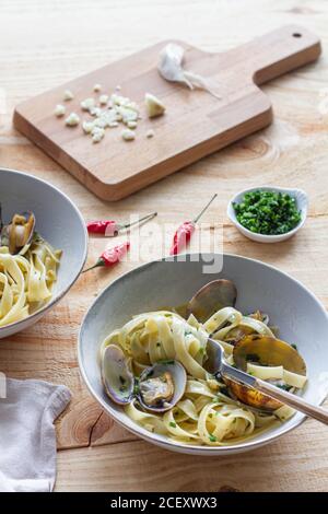 Grand angle de bol de spaghetti fraîchement cuits avec des palourdes placé sur une table en bois dans le café Banque D'Images