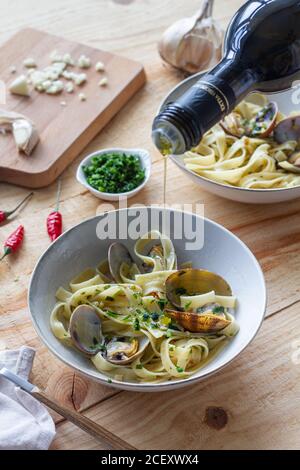 cuisson non reconnaissable verser l'huile d'olive dans un bol avec spaghetti et palourdes placées sur une table en bois dans le restaurant Banque D'Images