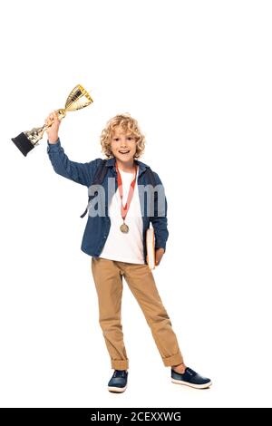 garçon blond avec médaille d'or tenant trophée et livre isolé sur blanc Banque D'Images