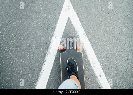 Vue de dessus de la récolte anonyme mâle debout sur la longue planche pendant promenade le long de la rue dans la ville Banque D'Images