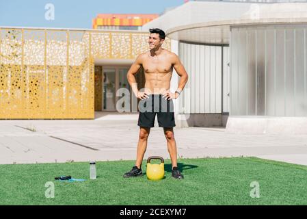 Ravie belle tenue athlète masculin debout sur la pelouse avec des sports équipement et sourire tout en se relaxant pendant l'entraînement en été Banque D'Images