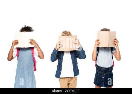 des écolières et des écoliers multiculturels couvrant des visages avec des livres isolés blanc Banque D'Images