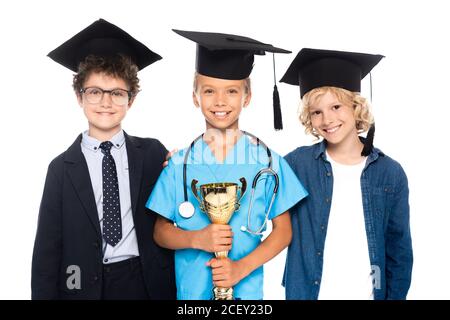 les enfants en casquettes de remise des diplômes vêtus de costumes de différentes professions trophée de maintien isolé sur blanc Banque D'Images