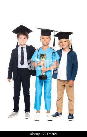 les enfants en calottes de remise des diplômes vêtus de costumes de différentes professions trophée de maintien isolé sur blanc Banque D'Images