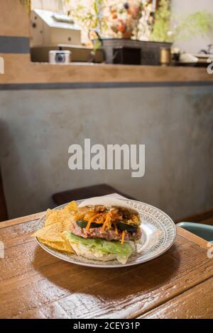 Gros plan de savoureux hamburger avec escalope de poulet et divers légumes sur plaque placée sur une table en bois dans la cuisine Banque D'Images