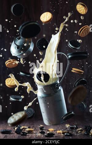 Divers cookies au chocolat et éclaboussures de lait en métal peuvent créer chaos au-dessus de la table en bois Banque D'Images