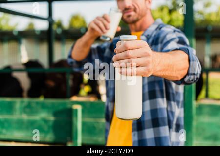 foyer sélectif de fermier dans chemise à carreaux contenant bouteille et verre de lait frais Banque D'Images