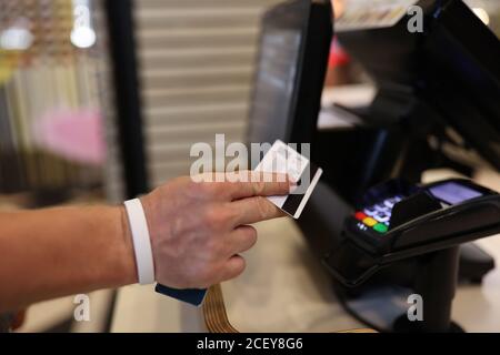 La main de l'homme tient une carte en plastique dans ses mains et l'applique au terminal. Banque D'Images