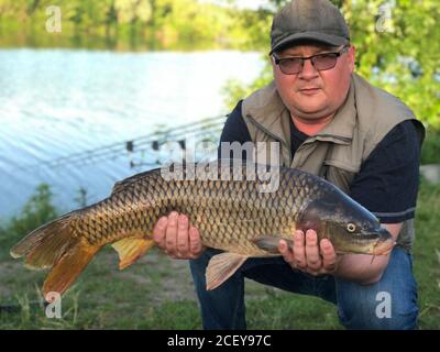 Pêche à la carpe. Pêcheur avec trophée de poisson dans les mains au lac Banque D'Images