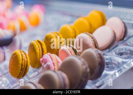Des rangées de gâteaux colorés de macarons à vendre sur le comptoir de la boutique de bonbons, du marché, du café ou de la boulangerie. Dessert, biscuit, sucreries et cuisine française traditionnelle Banque D'Images