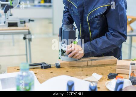 Menuisier professionnel utilisant une ponceuse électrique pour polir le bois sur un établi rugueux à l'atelier. Conception, menuiserie, savoir-faire et travail à la main Banque D'Images