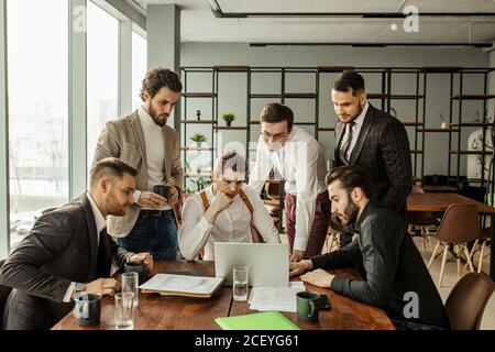 professionnels sérieux et confiants collègues au bureau, utilisant un ordinateur portable. les hommes en tuxedo en tenue formelle regardent l'écran de l'ordinateur portable et réfléchissent aux délais Banque D'Images