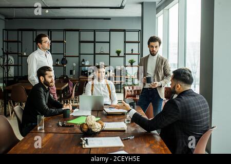 de jeunes chefs d'entreprise caucasiens se sont réunis en fonction pour un collègue, tiennent une réunion pour discussion et ont une coopération efficace, tout le monde vêtu de f Banque D'Images