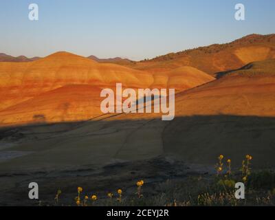 Les derniers rayons du soleil couchant la lumière bluffs loin derrière les collines peintes. De l'Oregon, USA. Banque D'Images