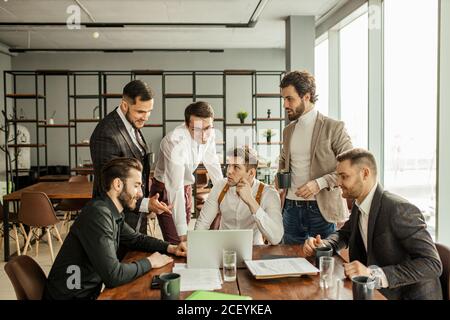 les gens d'affaires caucasiens réfléchis travaillent au bureau, en utilisant un ordinateur portable, regarder l'écran de l'ordinateur portable et développer une nouvelle entreprise de démarrage Banque D'Images