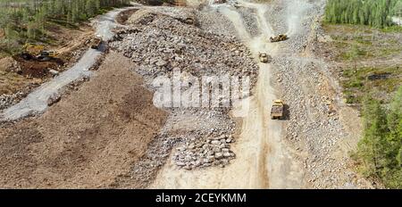 Photo de drone sur la construction d'une nouvelle autoroute - de nombreuses machines industrielles lourdes travaillent ensemble - les camions à benne basculante, le bulldozer et la pelle hydraulique retirent et déplacent expo Banque D'Images