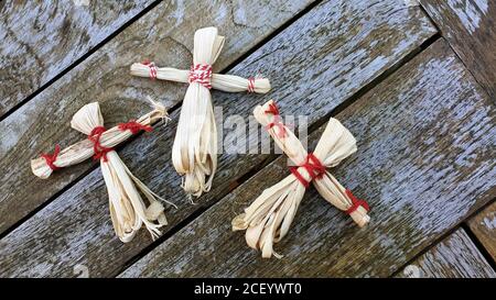 Trois poupées artisanales de cosse de maïs sur fond de bois, thème de récolte d'automne, charmes de bonne chance. Banque D'Images