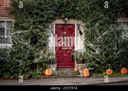 L'extérieur d'un cottage de campagne anglaise décoré pour Halloween avec des citrouilles à la porte et des toiles d'araignées ou des toiles d'araignée en descendant Banque D'Images