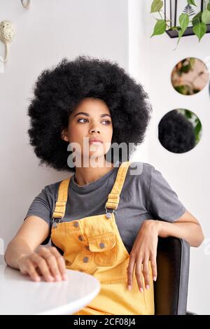 Femme africaine pensive attentionnés regardant par la fenêtre, assis à une table de café. Banque D'Images