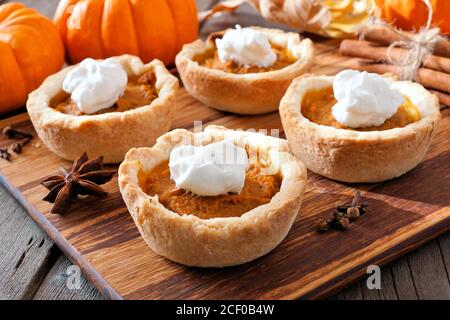 Mini tartes à tarte à la citrouille, scène de gros plan sur un serveur en bois sur un fond de bois rustique Banque D'Images