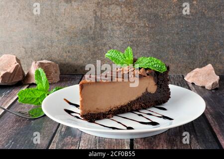 Tranche de cheesecake au chocolat sur l'assiette, encore la vie avec un fond brun rustique Banque D'Images