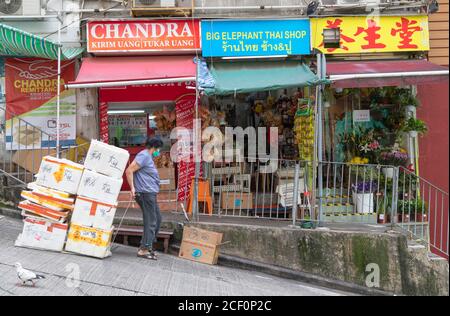 Femme passant devant les magasins, Sai Ying Pun, Hong Kong Island, Hong Kong Banque D'Images