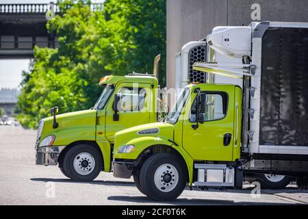 Poids moyen de transport professionnel engins puissants semi-camions industriels diesel avec des remorques à boîtes réfrigérées en rangée au quai de l'entrepôt portes pour Banque D'Images