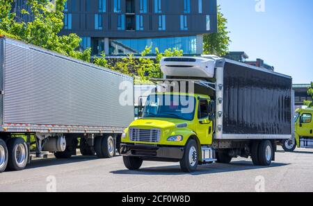 Poids moyen de transport professionnel engins puissants semi-camions industriels diesel avec des remorques à boîtes réfrigérées qui s'exécutent jusqu'au quai d'entrepôt pour le chargement carg Banque D'Images